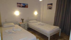 Una camera d'albergo con due letti singoli, un comodino, una lampada e due luci a parete.