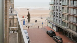 A view from a balcony overlooking a beach with a parking area and a building with balconies. - Spacious Coastal Retreat (Middelkerke)