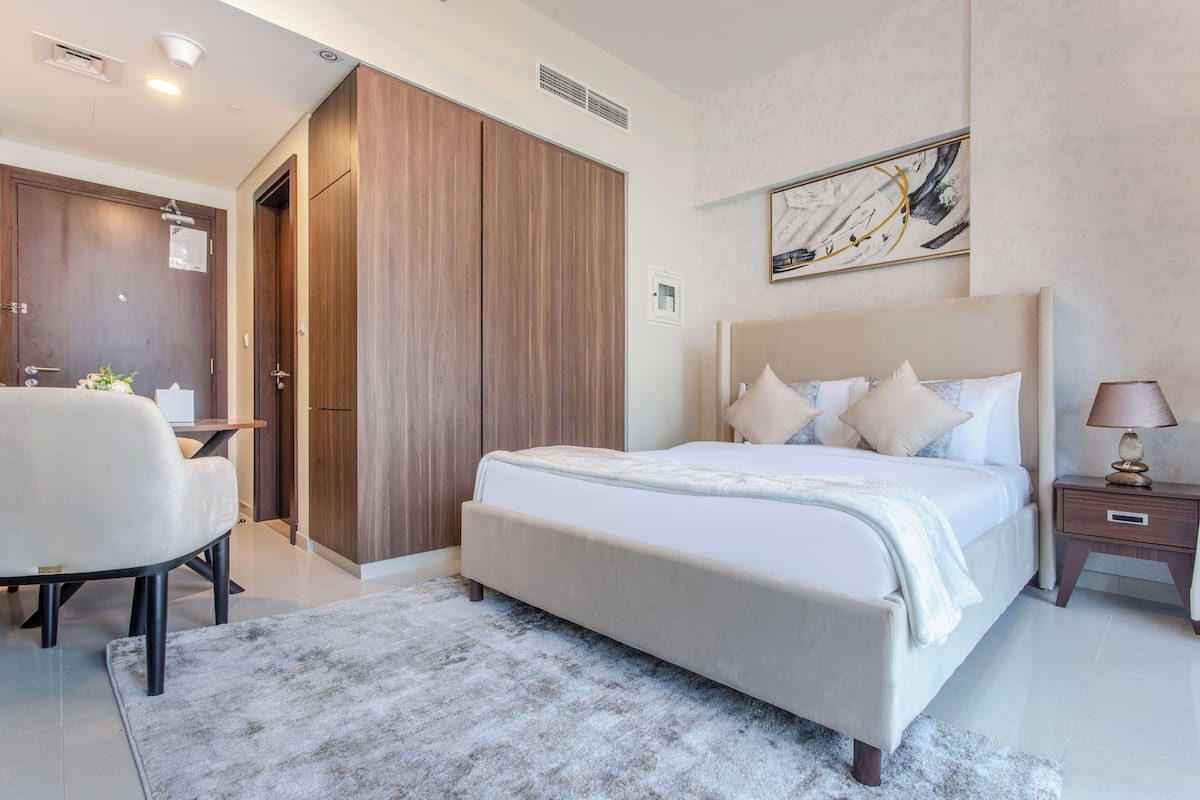 A modern bedroom with a large bed, a desk, and a wardrobe.