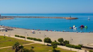 A coastal beach scene with a clear sky, a sandy shore, and a rocky breakwater. - Nice Apartment in the Marina of Almerimar (El Ejido)