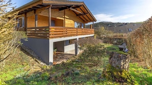 Une cabane en bois dotée d’un balcon, entourée de verdure et sous un ciel dégagé.