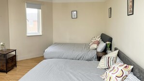 Quarto com duas camas, uma mesa pequena e uma janela.