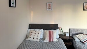 Quarto de hotel com duas camas, mesa de cabeceira e quadros com flores nas paredes.