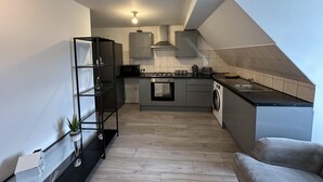 A compact kitchen with a washing machine, a microwave, and a toaster. - Oak Wembley Stadium Serviced Apartment by Edens (Wembley)