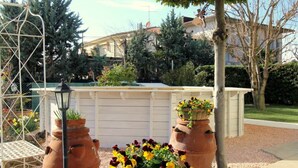 Un jardín con macetas de terracota y un enrejado metálico.