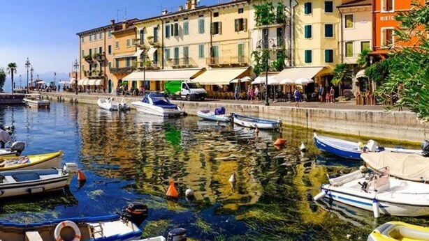 Un muelle con barcos amarrados, edificios con balcones y zonas de estar al aire libre.