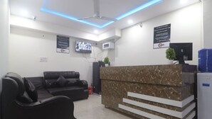Un área de recepción con un mostrador de mármol, sofás de cuero negro y un ventilador de techo.