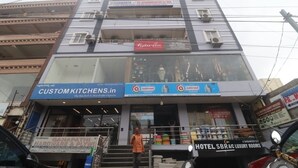 Un edificio de varios pisos que alberga distintos negocios, como una tienda de cocinas a medida, un hotel y un almacén de ferretería.