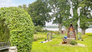Un jardin agrémenté d’un pilier en pierre, d’une structure en bois ressemblant à une nichoir et d’un banc.