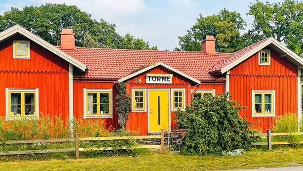 Un bâtiment en bois rouge avec une porte jaune et le numéro 34.
