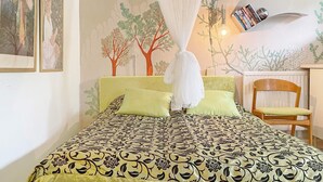 Une chambre à coucher comprenant un lit, une chaise, une bibliothèque et une fresque murale.
