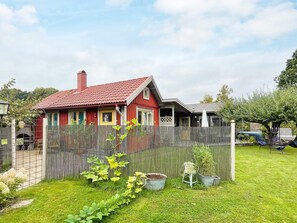 A red house with a fenced yard, a small garden, and a hammock. - 5 Person Holiday Home in Vaxjo (Växjö)