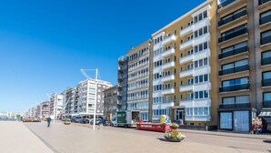 A multi-story building with balconies, a clear sky, and a paved walkway. - Apartment in Koksijde for 8 Person (Koksijde)