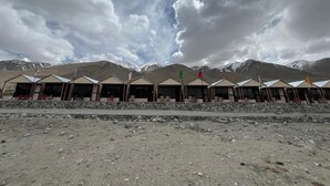 A row of tents with stone walls and a clear view of snow-capped mountains in the background. - Padma Cottage Pangong (Leh)
