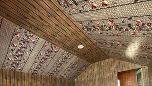 A bedroom with a wooden ceiling, a bed with white bedding, and a red carpet. - Padma Cottage Pangong (Leh)
