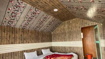 A bedroom with a wooden ceiling, a bed with white bedding, and a red carpet.