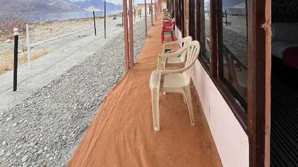 A covered outdoor seating area with a view of mountains. - Padma Cottage Pangong (Leh)