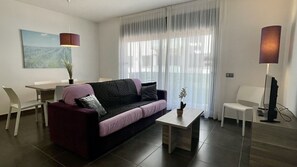 Un salon moderne comprenant un canapé, une table basse, une table à manger et un téléviseur.