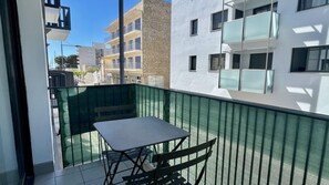 Ein Balkon mit Tisch und Stühlen mit Blick auf eine Stadtlandschaft und moderne Gebäude.