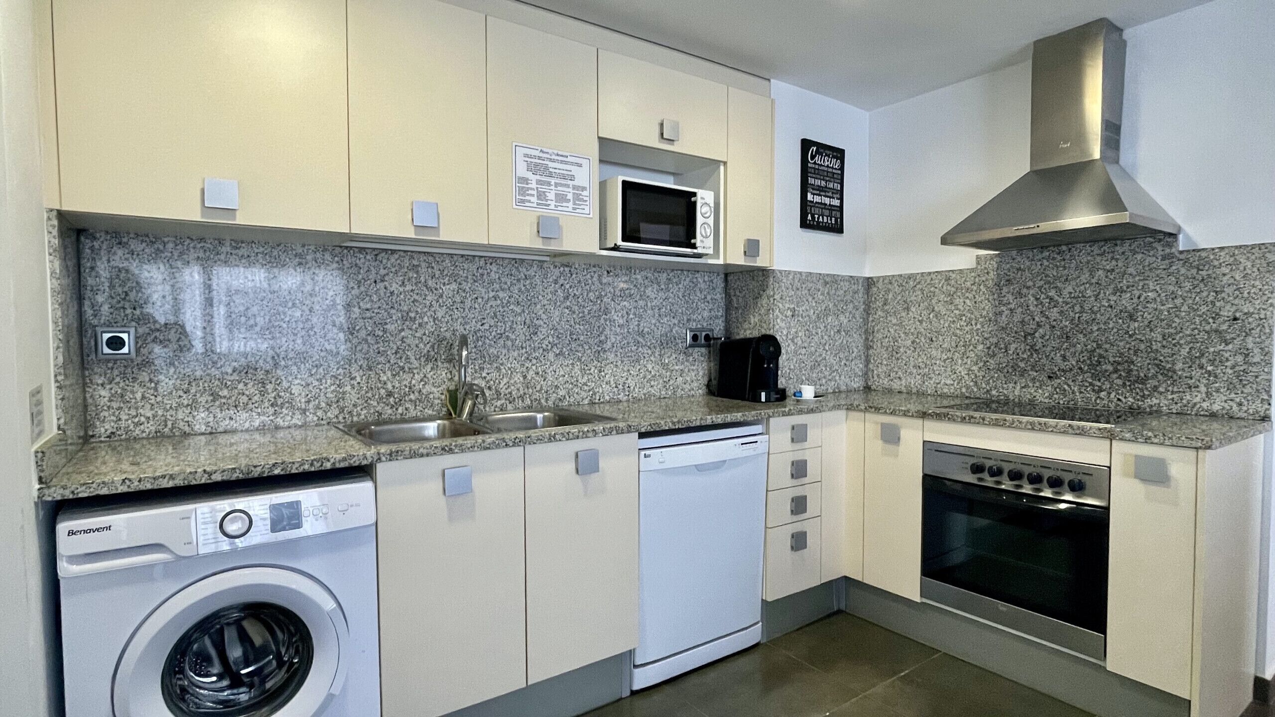 A compact kitchen with a washing machine, dishwasher, microwave, stove, and a sink.