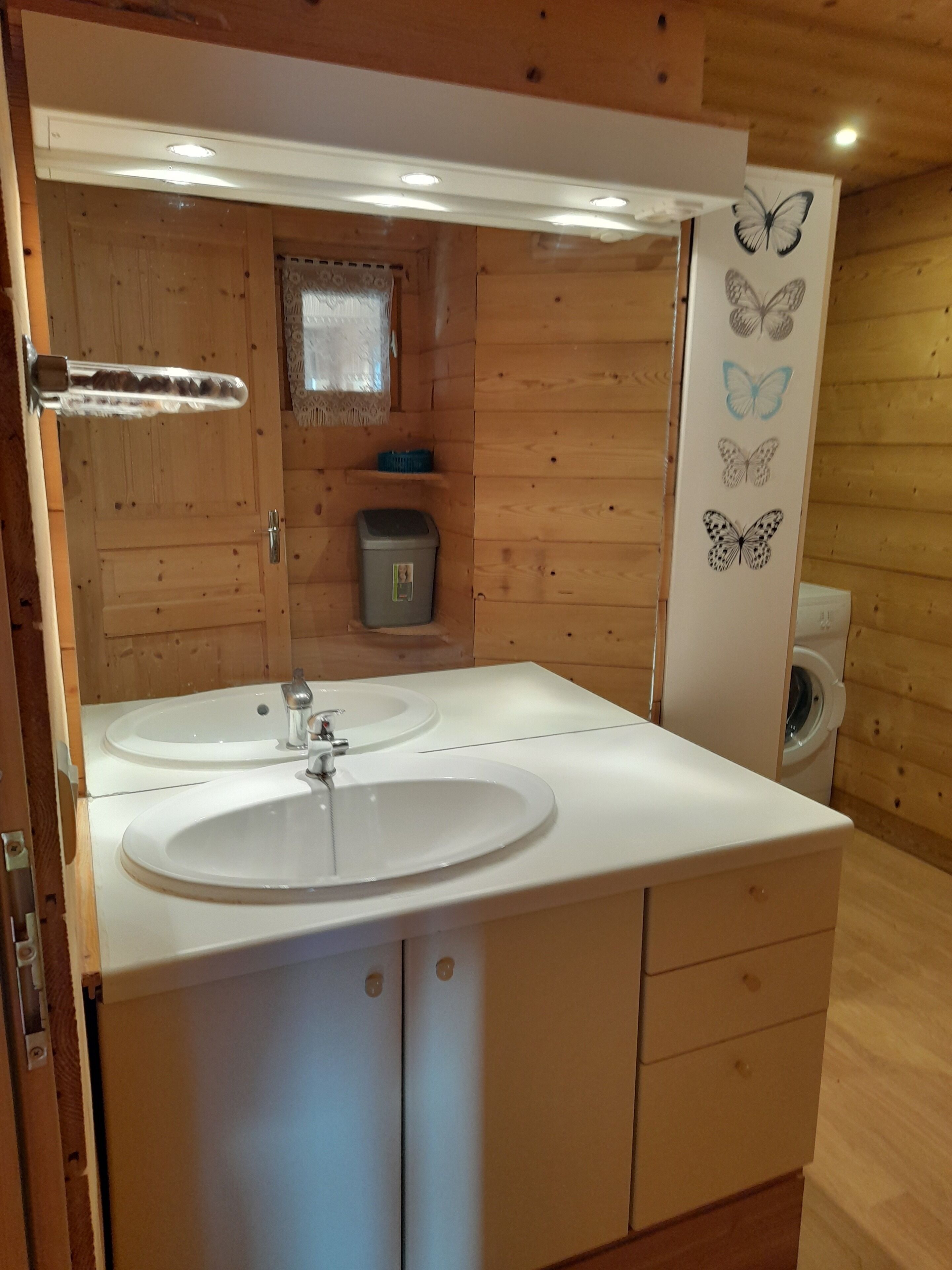 Et badeværelse i en træhytte med to håndvaske, et spejl og et toilet.
