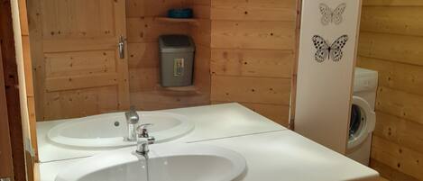 Et badeværelse i en træhytte med to håndvaske, et spejl og et toilet.
