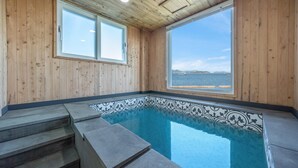 Une cabane en bois avec une petite piscine et vue sur la mer.