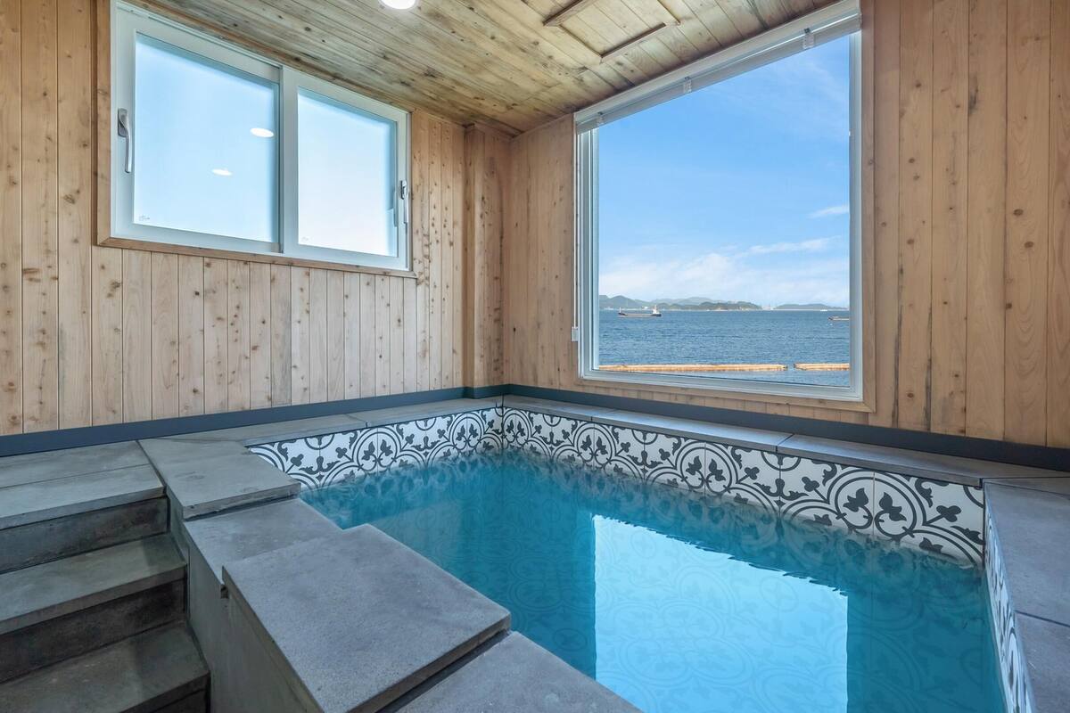 A wooden cabin with a small pool and a view of the sea.
