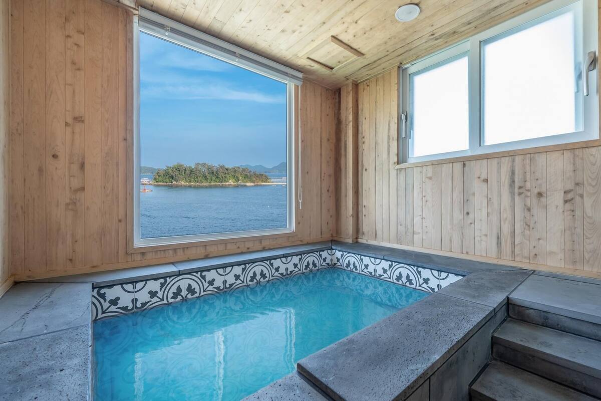 A wooden cabin with a small pool and a view of the sea.