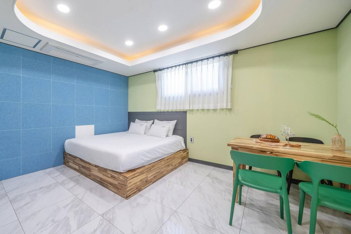 A modern bedroom with a bed, a desk, and chairs.