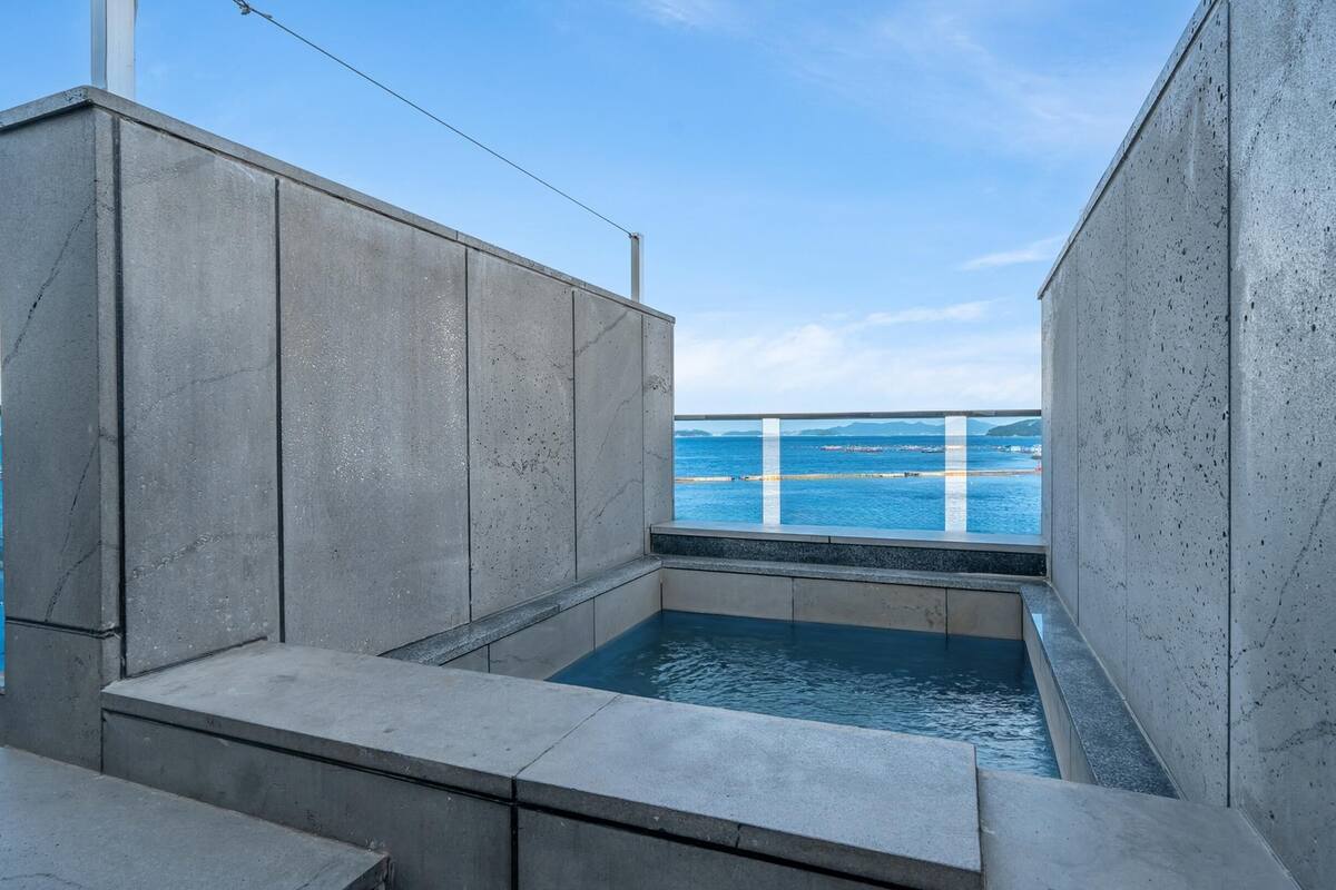 A concrete infinity pool with a view of the sea and distant land.