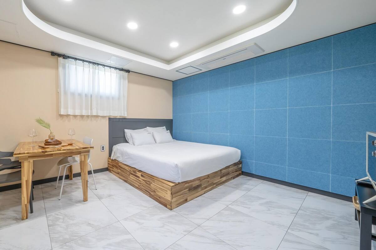 A bedroom with a bed, a desk, and a chair.