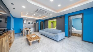 Un salon moderne avec un canapé bleu, une table basse en bois et un coin cuisine comprenant un ensemble de salle à manger.