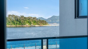 Une vue depuis une fenêtre donnant sur une étendue d’eau, avec une île boisée et des montagnes à l’horizon.