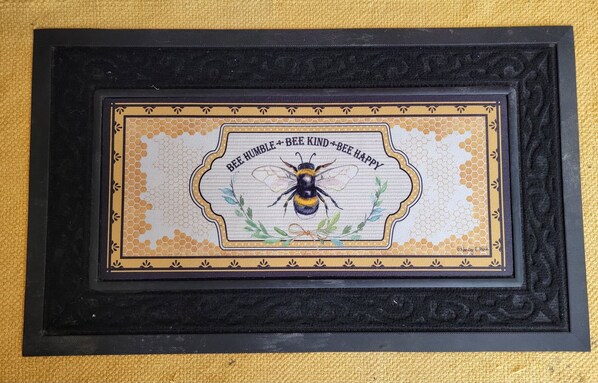 A framed welcome sign with a bee illustration and the text "BEE HUMBLE - BEE KIND - BEE HAPPY".