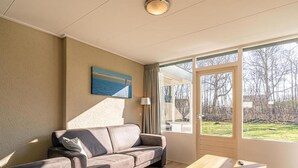 Un salon moderne avec un canapé, une table basse et une grande fenêtre donnant sur l’extérieur.