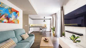 A modern living room with a sofa, coffee table, and a TV mounted on the wall. - Apartamentos Turísticos Metrópolis (Cartagena)