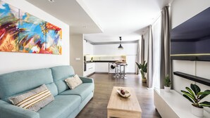 A modern living room with a teal sofa, a wooden coffee table, and a colorful abstract painting. - Apartamentos Turísticos Metrópolis (Cartagena)
