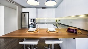 A modern kitchen with a wooden island, two pendant lights, and stainless steel appliances. - Apartamentos Turísticos Metrópolis (Cartagena)