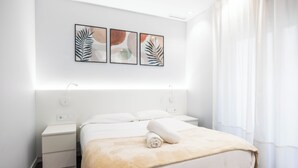 A modern hotel room with a neatly made bed, a bedside table, and a wall-mounted artwork above the bed. - Apartamentos Turísticos Metrópolis (Cartagena)