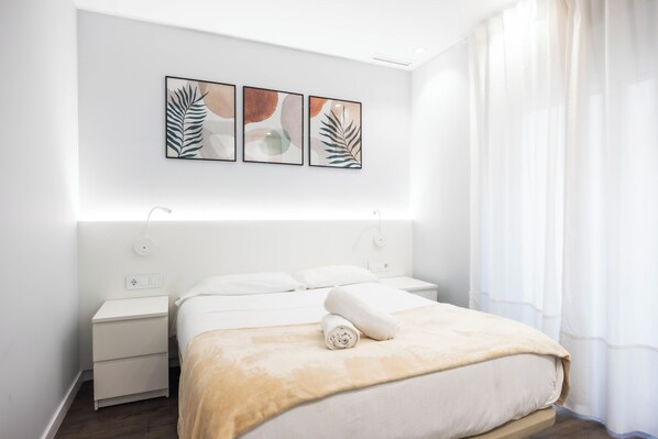 A modern hotel room with a neatly made bed, a bedside table, and a wall-mounted artwork above the bed. - Apartamentos Turísticos Metrópolis (Cartagena)