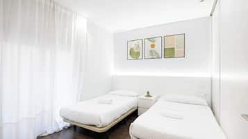 Una habitación de hotel con dos camas individuales, una mesita de noche con una planta y una pared decorada con tres cuadros enmarcados.