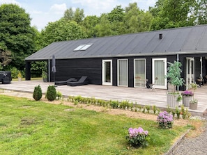 Un bâtiment moderne doté d’un toit plat, de grandes fenêtres et d’un patio couvert avec des espaces pour s’asseoir à l’extérieur.