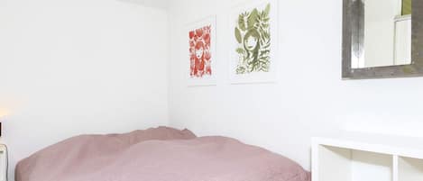 A bedroom with a bed, a white dresser, and two wall-mounted artworks.