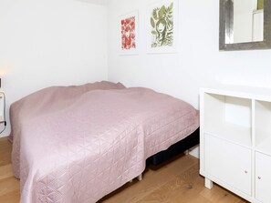 A bedroom with a bed, a white dresser, and two wall-mounted artworks. - 4 Star Holiday Home in Skals (Skals)