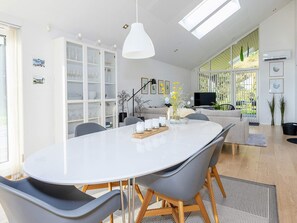 A modern dining area with a white oval table, grey chairs, and a pendant light.