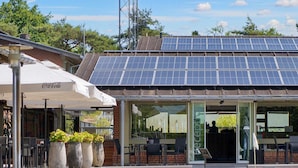 A building with a solar panel roof, outdoor seating with umbrellas, and a Coca-Cola branded sign. - 6 Person Holiday Park Home in Gilleleje (Gilleleje)