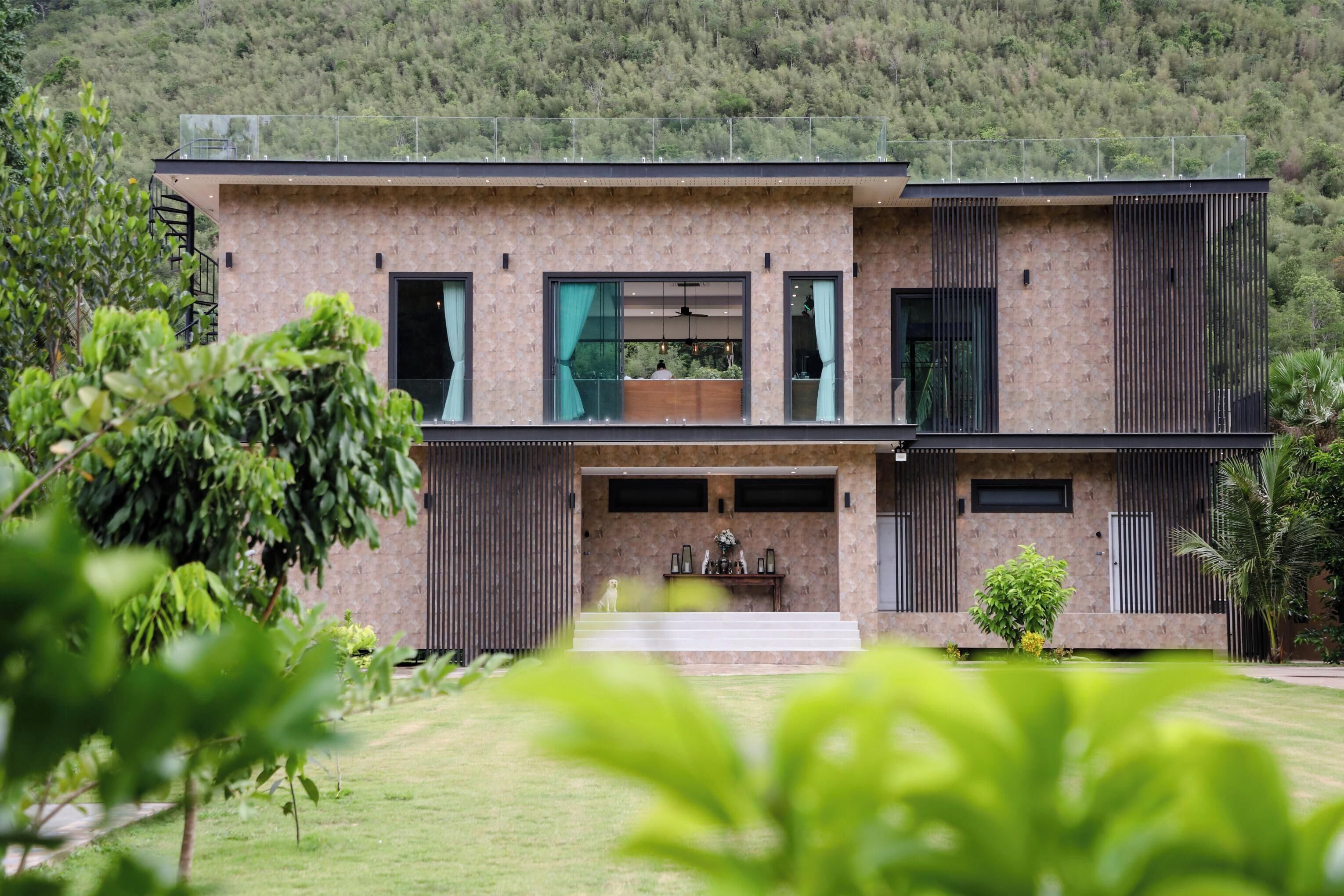 A modern two-story house with a stone facade, large windows, and a balcony.
