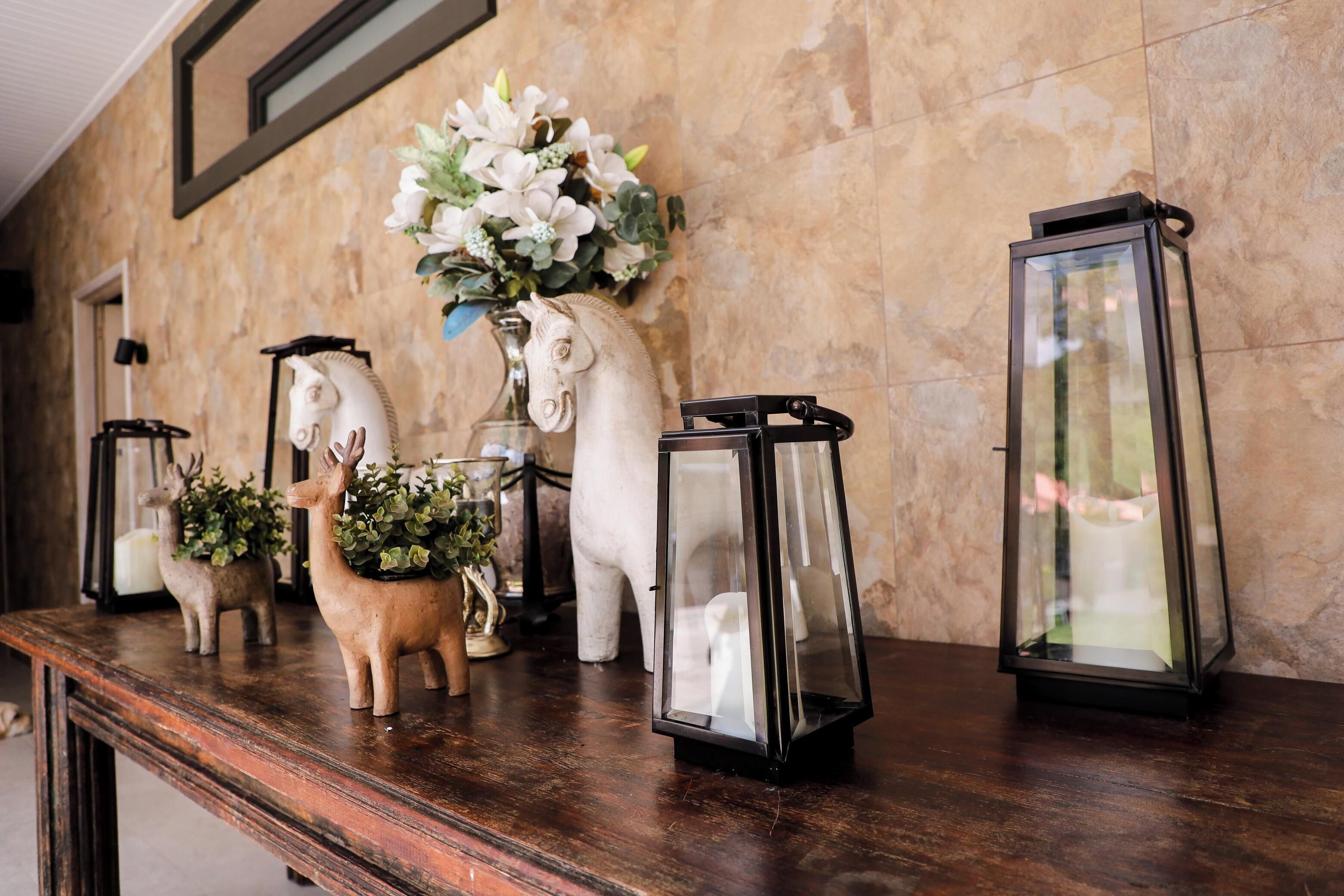 A wooden table with decorative items including a white horse sculpture, a deer sculpture, and two lanterns.