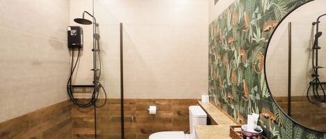 A bathroom with a glass-enclosed shower, a toilet, and a sink with a mirror.